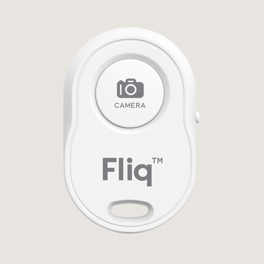 Fliq Bluetooth Remote in hand triggering smartphone camera remotely
